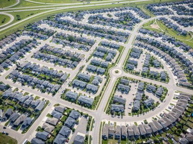 Birçok evi ve geniş yuvarlak kavşağı olan bir banliyö mahallesi. Evlerin çoğu beyaz ve caddelerde park etmiş bir sürü araba var.