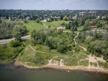 Ortasında park olan bir şehir manzarası. Park ağaçlarla çevrili ve ona giden bir yol var.