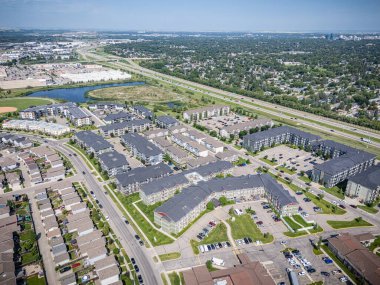 Bir sürü evi ve büyük bir otoparkı olan bir yerleşim yeri manzarası. Gökyüzü açık ve güneş parlıyor.
