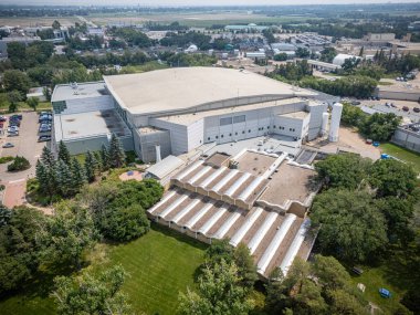 Bir sürü penceresi ve yeşil çatısı olan büyük bir bina. Bina ağaçlar ve otlarla çevrili.