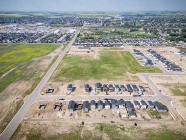 Evleri ve birkaç arabası olan bir yerleşim yeri manzarası. Evlerin çoğu beyaz ve bölgede park etmiş birkaç araba var.