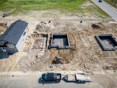 Kamyonu ve vinci olan bir inşaat alanı. Vinç büyük bir ekipman kaldırıyor.