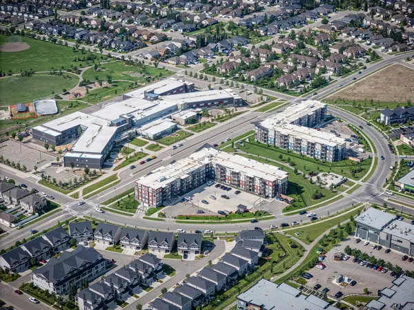 Şehir caddesi manzaralı, merkezinde büyük bir apartman kompleksi var. Cadde başka apartmanlarla çevrili.