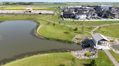 Ortasında bir çeşme olan büyük bir su kütlesi. Su yeşil ve sakindir. Çevresi evleri ve ağaçları olan bir yerleşim yeri.