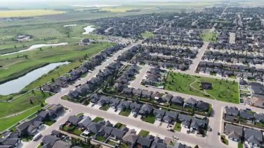 Evleri ve parkı olan bir yerleşim yeri. Evler dizildi ve caddeye park edilmiş bir sürü araba var.