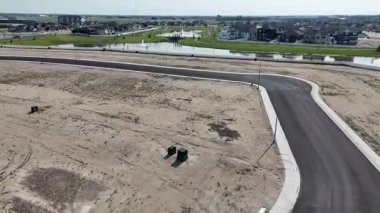 Yol, arka planda birkaç evle birlikte uzakta gösteriliyor. Yol boş ve o bir yerleşim yeri.