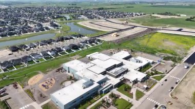 Okul yukarıdan park yeri ve çimenli bir alanla gösteriliyor. Okul evler ve büyük bir tarla ile çevrilidir.