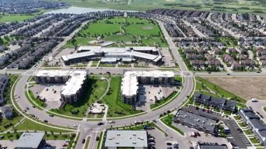 Merkezinde büyük bir bina bulunan bir yerleşim yeri manzarası. Binaların çoğu beyaz ve caddeye park edilmiş bir sürü araba var.