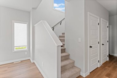 Beyaz merdivenli ve pencereli bir koridor. Koridor boş ve merdiven tahtadan yapılmış.