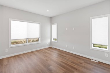 Beyaz duvarları ve ahşap zemini olan büyük bir oda. Oda boş ve iki penceresi var. Pencereler beyaz panjurlarla kaplı.