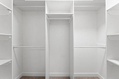 Dolapta beyaz duvarlar ve raflarla büyük bir yürüyüş. Dolap boş ve askılarda hiç giysi yok.