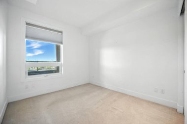 Şehir manzaralı beyaz bir odada büyük bir pencere. Oda boş ve minimalist bir görünüşü var.