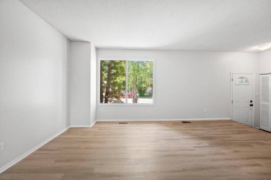 Penceresi ve kapısı olan büyük, boş bir oturma odası. Oda çok temiz ve çok rahat görünüyor.