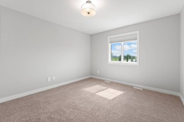 Beyaz tavanı ve penceresi olan büyük, boş bir oda. Oda çıplak ve dağınık. Mobilya ya da dekorasyon yok. Pencere içeri doğal ışık salıyor, parlak ve havadar bir atmosfer yaratıyor.