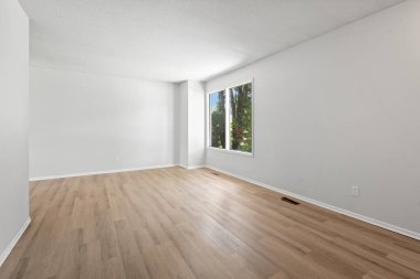 Büyük, penceresi ve beyaz duvarı olan boş bir oda. Oda boş ve boş. Mobilya ya da dekorasyon yok. Pencere içeri doğal ışık salıyor, parlak ve havadar bir atmosfer yaratıyor.