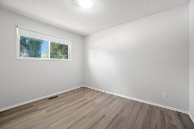 Ahşap zemini ve penceresi olan büyük, boş bir oda. Oda çok temiz ve minimalist bir havası var.