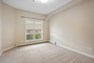 Penceresi ve radyatörü olan bir oda. Oda boş ve düz beyaz bir duvarı var.