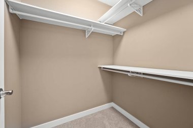 Beyaz rafları ve beyaz kapısı olan küçük, boş bir dolap. Oda çok temiz ve dağınık.