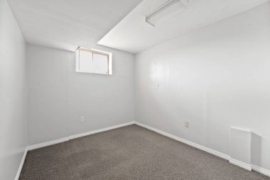 Beyaz duvarı ve penceresi olan küçük, boş bir oda. Oda çıplak ve dağınık. Mobilya ya da dekorasyon yok. Beyaz duvarlar ve halılı zemin odayı temiz ve basit bir şekilde gösteriyor.