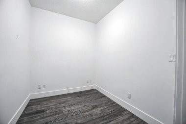 Beyaz duvarı ve ahşap zemini olan küçük, boş bir oda. Oda çıplak ve dağınık. Mobilya ya da dekorasyon yok. Uzay soğuk ve verimsiz, sıcaklıktan ve kişilikten yoksun.