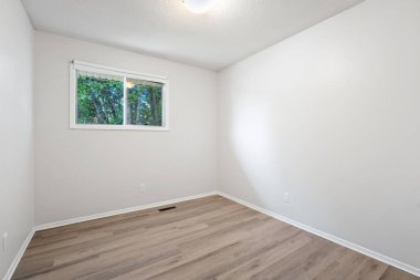 Penceresi ve ışığı olan çok boş bir oda. Oda çok temiz ve çok basit bir tasarımı var.