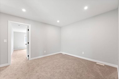 Başka bir odaya açılan kapısı olan beyaz bir oda. Oda boş ve minimalist bir görünüşü var.