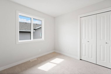 Penceresi ve dolabı olan beyaz bir oda. Oda boş ve minimalist bir görünüşü var.