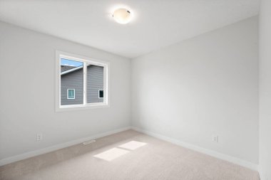 Penceresi ve lambası olan beyaz bir oda. Oda boş ve minimalist bir görünüşü var.