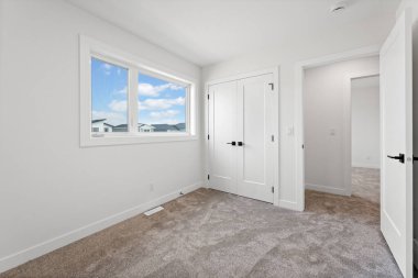 Penceresi ve kapısı olan bir yatak odası. Oda boş ve minimalist bir görünüşü var.