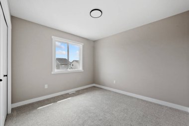 Büyük, penceresi ve beyaz duvarı olan boş bir oda. Oda çıplak ve dağınık. Mobilya ya da dekorasyon yok. Pencere içeri doğal ışık salıyor, parlak ve havadar bir atmosfer yaratıyor.