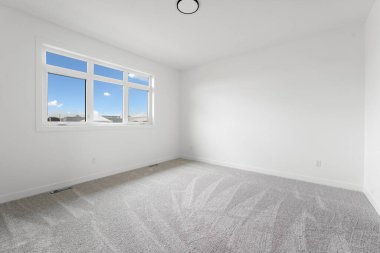 Büyük, penceresi ve beyaz duvarı olan boş bir oda. Oda çıplak ve dağınık. Mobilya ya da dekorasyon yok. Pencere içeri doğal ışık salıyor, parlak ve havadar bir atmosfer yaratıyor.