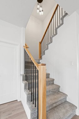 Üzerinde ahşap korkuluk ve lamba olan bir merdiven. Merdiven ahşaptan yapılmıştır ve siyah beyaz bir halısı vardır.