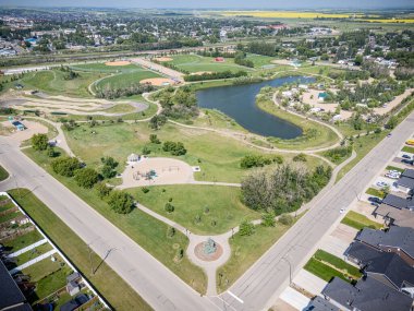 Ortasında bir heykel olan bir park yeri. Park evlerle çevrili ve bir sürü yeşil çimeni var.