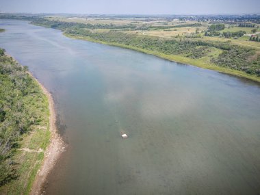 Üzerinde yüzen bir tekne olan nehir. Su sakin ve berrak. Gökyüzü mavi ve arka planda ağaçlar var.