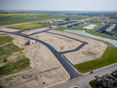 Ortasında yol olan bir yerleşim yeri manzarası. Yol evler ve büyük bir su kütlesiyle çevrilidir.