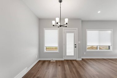 Tavandan sarkan avizesi olan büyük bir oda. Oda boş ve modern bir görünüşü var.