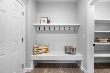 Beyaz bank, üzerinde sepet ve yastık olan bir koridorda oturuyor. Bankta kimse yok, koridor temiz ve dağınık.