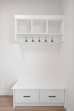 Beyaz bir duvarın önünde iki çekmeceli beyaz bir bank oturuyor. Tezgah boş ve duvar boş.