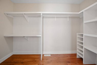 Rafları ve masası olan beyaz bir dolap. Dolap boş ve duvarlar beyaz. Odanın temiz ve düzenli bir görünüşü var.