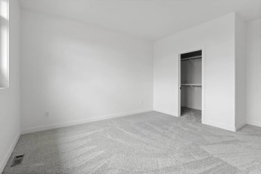 Beyaz kapısı ve beyaz dolabı olan beyaz bir oda. Oda boş ve minimalist bir görünüşü var.