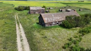 Toprak yolu ve iki eski binası olan kırsal bölge. Binalar uzakta ve terk edilmiş gibi görünüyor. Sahne yalnızlık ve sessizliktir.