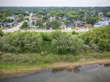İçinden nehir akan bir yerleşim bölgesinin manzarası. Evler dağılmış ve arka planda ağaçlar var.