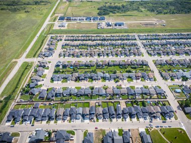 Birçok evi ve birkaç arabası olan bir yerleşim yeri. Evler çoğunlukla beyaz ve çimenler yeşil.