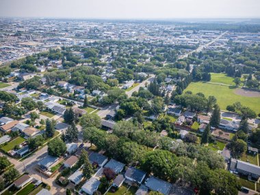 Şehir manzarası yukarıdan evler ve ağaçlarla çevrili. Evler çoğunlukla beyaz ve ağaçlar yeşil.