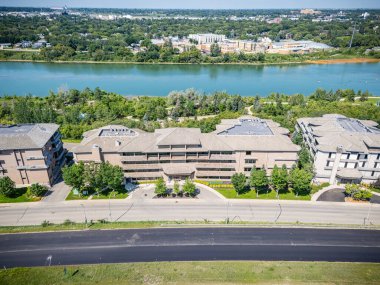 Şehrin diğer tarafında bir sıra apartmanı olan bir nehir manzarası. Binalar uzun ve modern bir tasarıma sahip. Nehir sakin ve huzurlu. Çevresi yemyeşil.