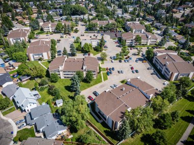 Bir sürü evi ve büyük bir otoparkı olan bir yerleşim yeri manzarası. Evlerin hepsi farklı boyutlarda ve tarzlarda, ve otopark arabalarla dolu. Sahne huzurlu ve sessiz.