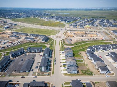 Bir sürü evi ve birkaç arabası olan bir yerleşim yeri. Evlerin çoğu beyaz ve arabalar caddeye park edilmiş.