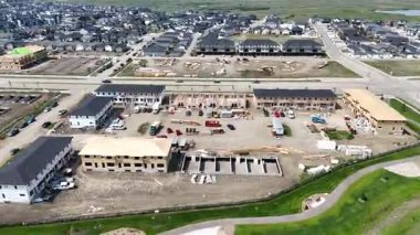 Ortasında inşaat alanı olan bir yerleşim yeri. Evler inşa ediliyor ve bölgede park edilmiş bir sürü araba var.