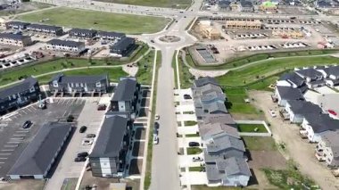 Evleri ve kavşağı olan bir yerleşim yeri. Evlerin çoğu beyaz ve caddeye park edilmiş bir sürü araba var.