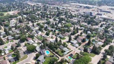 Evleri ve havuzu olan bir banliyö mahallesi. Evler dizildi ve caddeye park etmiş birkaç araba var.